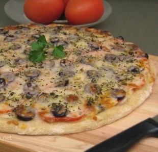 Homemade Mediterranean style pizza topped with olives and tomatoes, along with parsley for garnish.